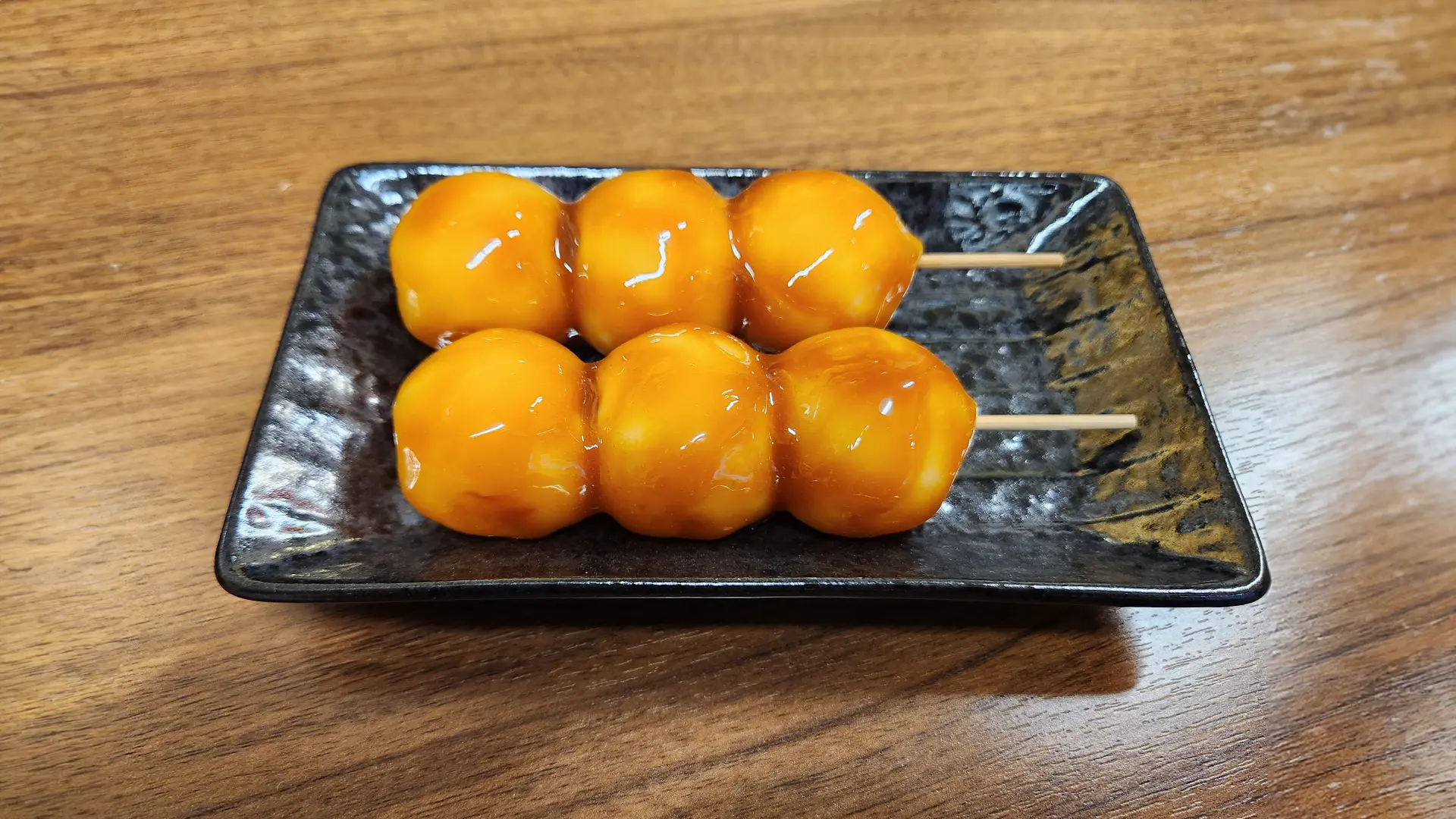 黒い皿にのった二串のみたらし団子